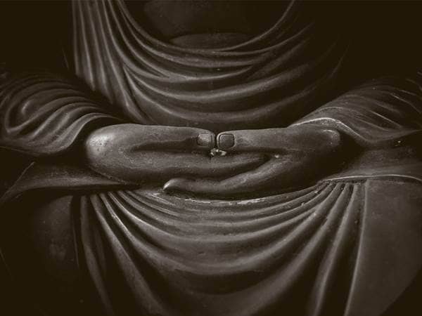 folded hands of a buddhist statue