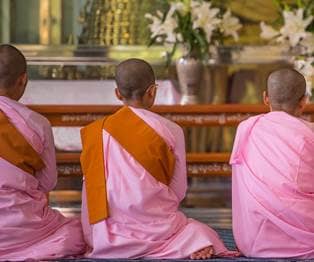 Buddhist nuns sit on the floor, meditate and pray, Mandalay, Myanma.