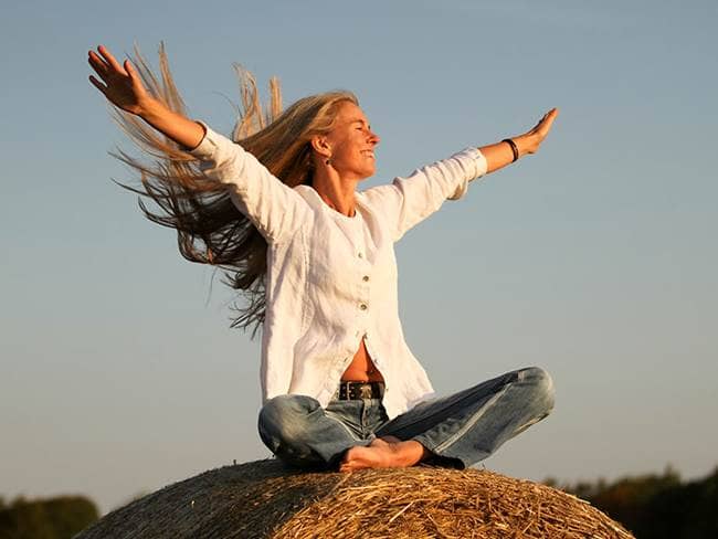 woman on mountain top with her arms up