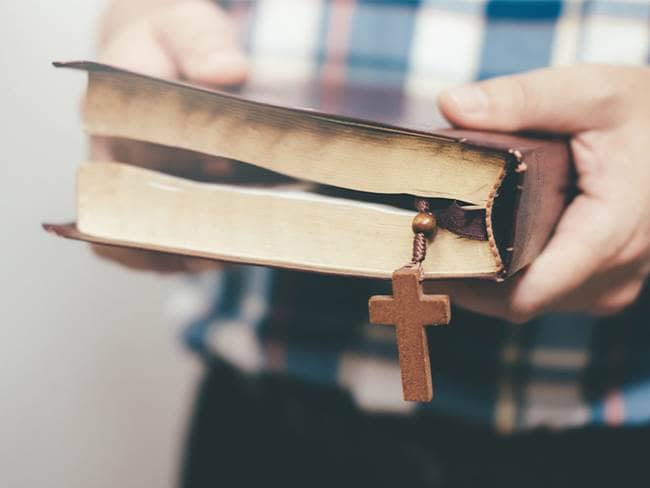 man holding a bible with a cross bookmark